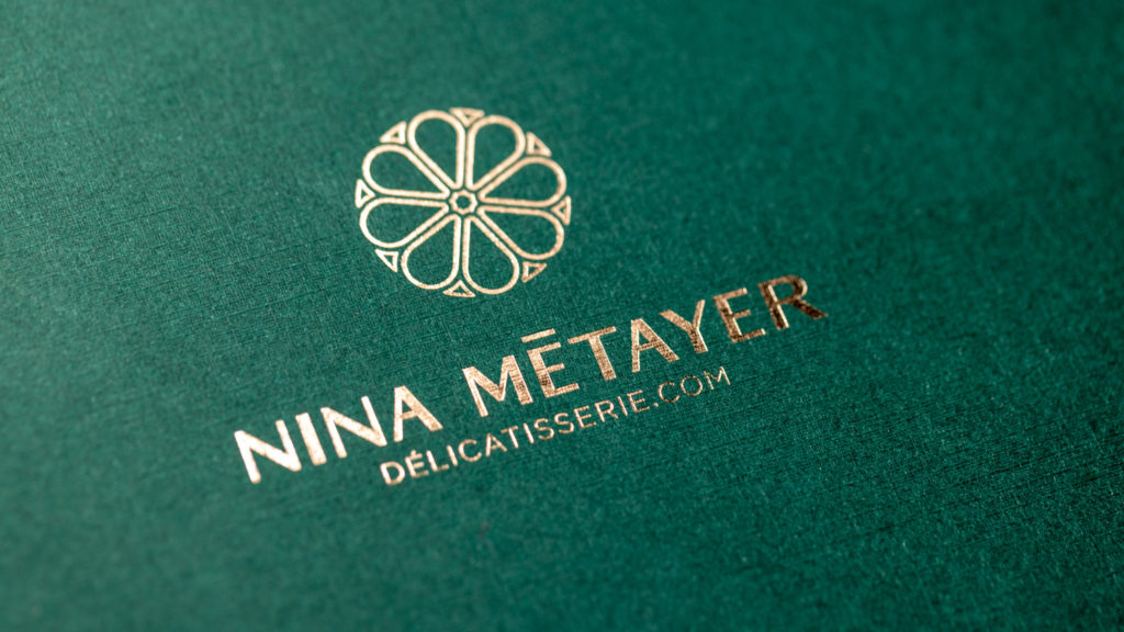 Logo Nina Métayer marqué à chaud or sur papier vert